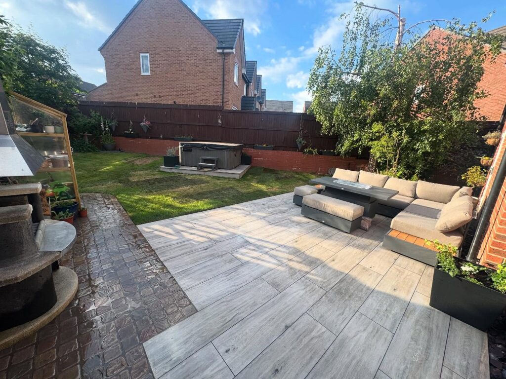 patio layed using decking wood paving slaps with corner sofa on it .